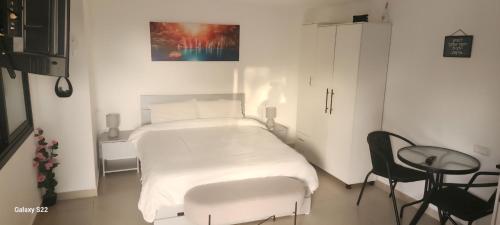 a white bed in a room with a table and a chair at שקט בערבה in Sappir