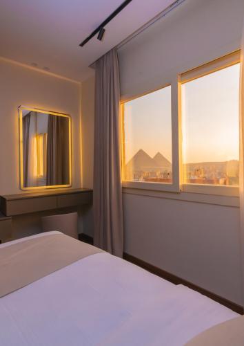 a bedroom with a bed and two windows at Spire West Hotel in Cairo