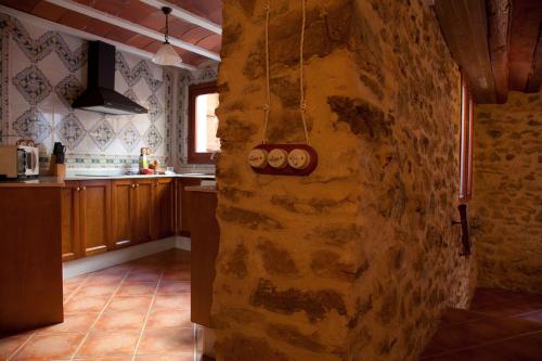 a kitchen with a stone wall with pots and pans at Casa Abuelina in Titaguas