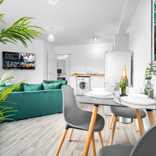 a living room with a green couch and a table and chairs at Stylish Two Bed Apartment - Parking - Sleeps 3 - Netflix 55C in Sleightholme
