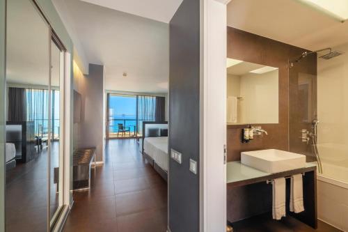 a bathroom with a sink and a bed in a room at RR Hotel da Rocha in Portimão