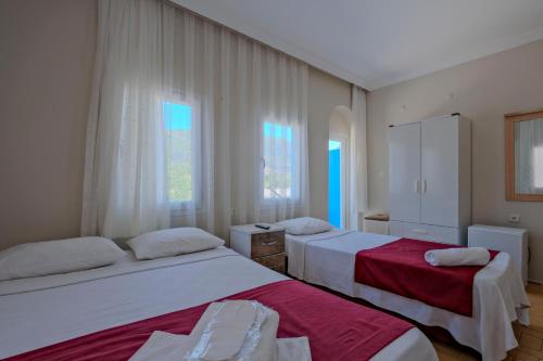a bedroom with two beds and two windows at Otel DENİZYILDIZI CENTRUM in Fethiye