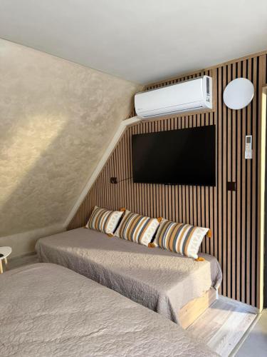 a bedroom with two beds and a tv on the wall at ValMar Guest rooms in Haskovo
