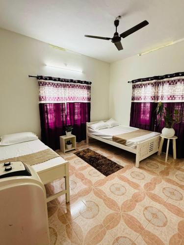 a room with two beds and purple curtains at Jimmy nivas in Kottayam