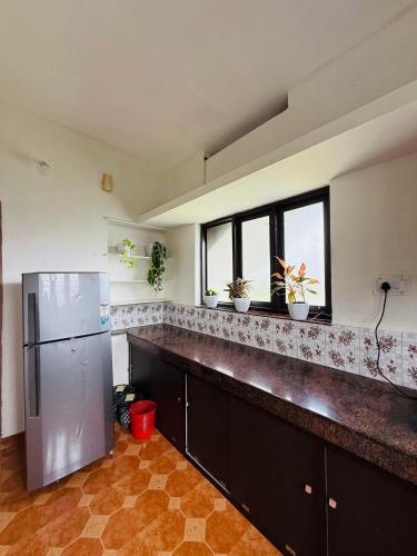 a kitchen with a stainless steel refrigerator and two windows at Jimmy nivas in Kottayam
