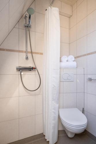 a bathroom with a shower curtain and a toilet at Yn 'e Haven Logies in Earnewâld