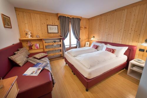 a bedroom with a large bed and a couch at Hotel Posta in Livigno