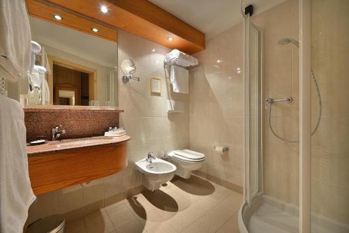 a bathroom with a toilet and a sink and a shower at Hotel Posta in Livigno
