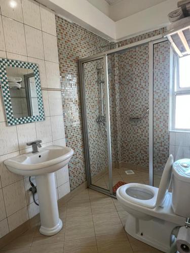 a bathroom with a shower and a toilet and a sink at Vine Gardens & Hotel, Mityana in Mityana