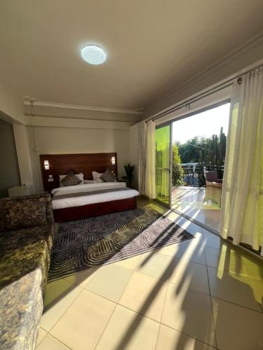 a bedroom with a bed and a large window at Vine Gardens & Hotel, Mityana in Mityana