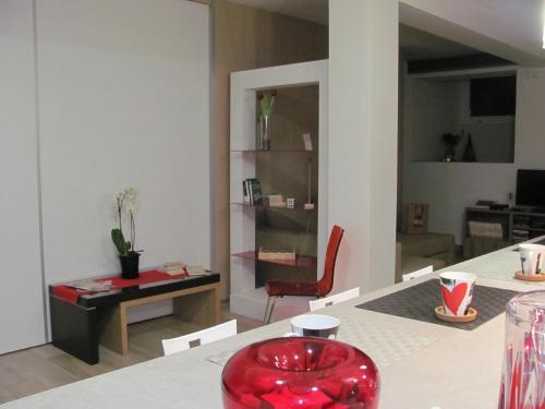 a living room with a table and a red chair at Folco Studio Apartment in Piazza Armerina