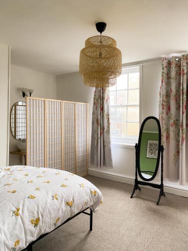 a bedroom with a bed and a mirror and a chandelier at Cozy en suite room in King's Lynn