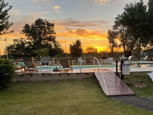 a swimming pool with chairs and a wooden bridge at complejo cumelen in Gualeguaychú