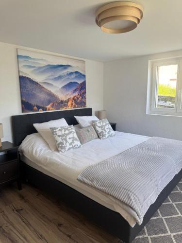 a bedroom with a bed with a painting on the wall at Chez Leny in Monthey