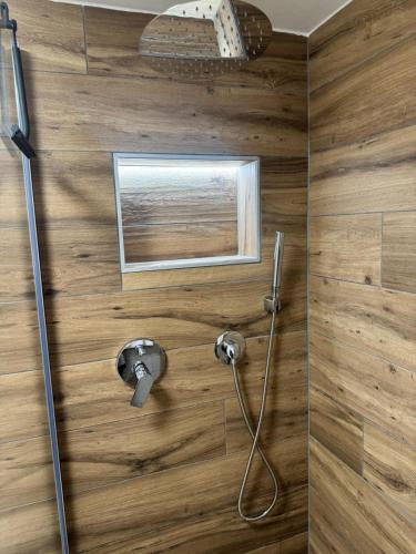 a shower with a hose attached to a wooden wall at Chez Leny in Monthey