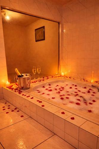 a bath tub filled with red rose petals and wine glasses at Classik Prime Motel in Araçatuba