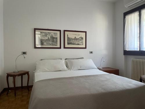 a bedroom with a white bed with two pictures on the wall at Sarnico Terrazza sul lago di Iseo in Sarnico