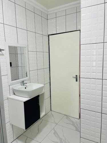 a white bathroom with a sink and a mirror at Xitshavani Lodge in Phalaborwa