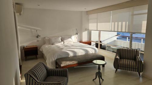 a bedroom with a bed and two chairs and a balcony at Le Grand Hotel Ilo in Ilo
