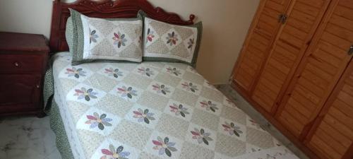 a bedroom with a bed with a floral bedspread and pillows at Zerarda in Saïss