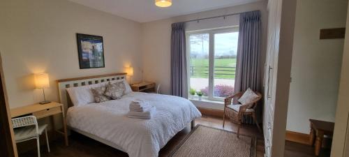 a bedroom with a bed and a large window at Three Hares Farmhouse, Galway in Craughwell