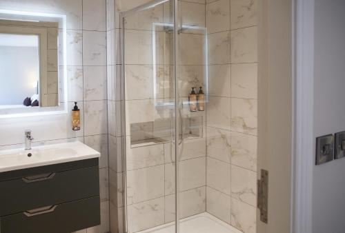 a bathroom with a shower with a sink and a mirror at Kerry Coast Hotel in Cahersiveen