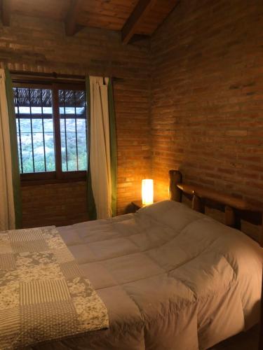 a bedroom with a large bed and a window at Hermosa Cabaña El Nogalito Mina Clavero in Mina Clavero