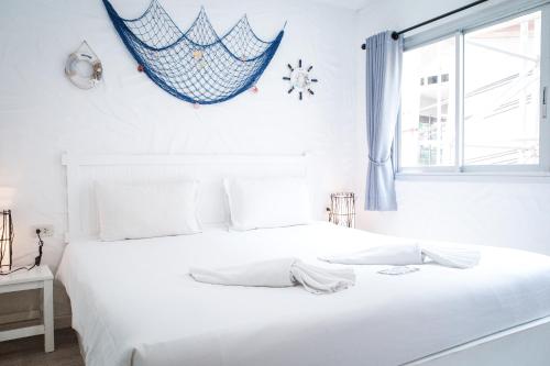 a white bedroom with a large white bed and a window at Phi Phi Indigo Hotel in Phi Phi Islands