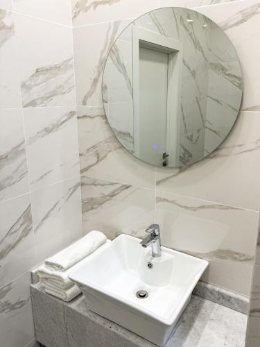 a white bathroom with a sink and a mirror at River Stone in Pavlodar