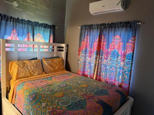 a bedroom with a bed with a colorful comforter and curtains at Montego Bay, Ironshore Luxury Studio in Montego Bay