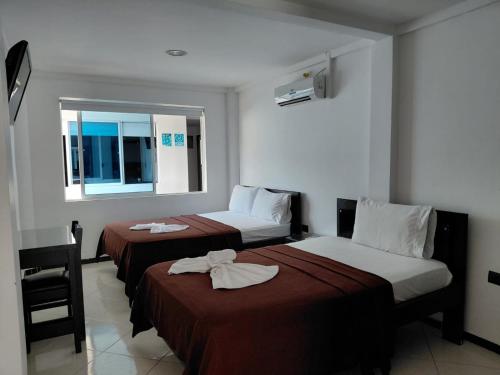 a hotel room with two beds and a window at Hotel Los Potrillos in Aguazul