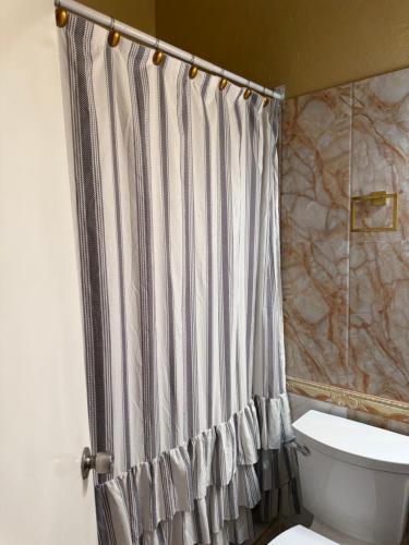 a bathroom with a shower curtain and a toilet at Montego Bay, Ironshore Luxury Studio in Montego Bay