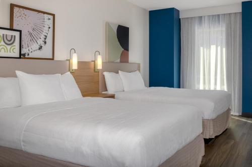 two beds in a hotel room with blue walls at Spark By Hilton Montreal Midtown in Montreal