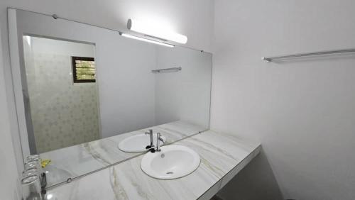 a bathroom with two sinks and a mirror at L'île de Marie-Jo in Assinie