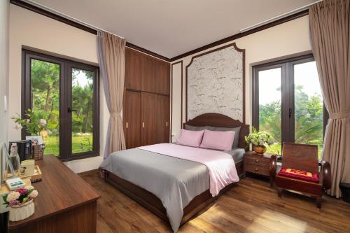 a bedroom with a bed and a desk and windows at Song Đan Villa in Sóc Sơn