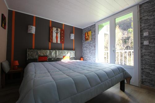 a bedroom with a large bed and a large window at Maison au bord de l'eau avec Jacuzzi in Millau