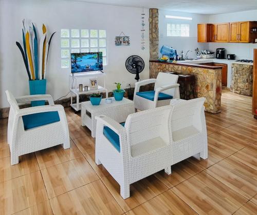 a living room with white wicker chairs and a table at Gaia - Casa de Playa in San Bernardo del Viento