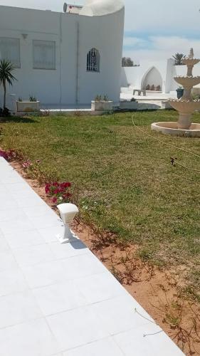 a white bench sitting on the side of a sidewalk at Villa privee Narjess grande piscine et jacuzzi in Taguermess