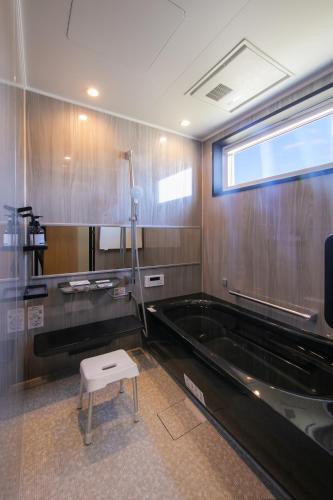 ein Badezimmer mit Badewanne und Hocker darin in der Unterkunft Trattoria&BarTroppo in Hayaki
