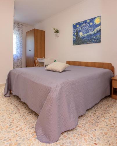 a bedroom with a large bed with a purple blanket at Casaverde Gargano in Mattinata