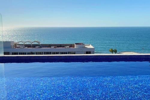 a swimming pool with a view of the ocean at Beautiful apartment just 1 block from the beach. in Mazatlán