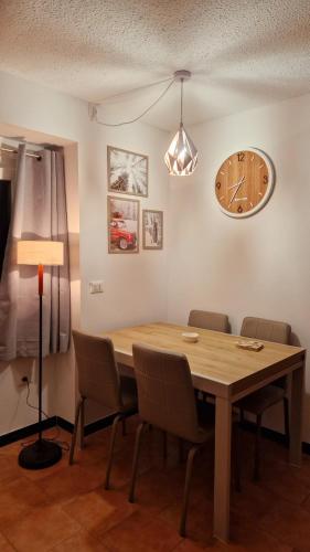 a dining room table with chairs and a clock on the wall at Il Cuore del Tonale in Passo del Tonale