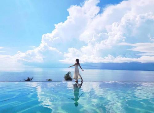 a woman standing in the water in the middle of the ocean at The Seafront Condotel - Apec Mandala in Mui Ne