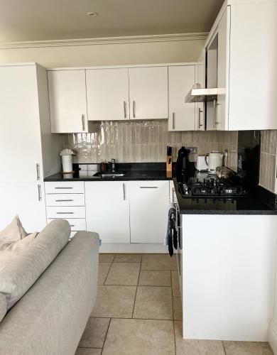 a white kitchen with white cabinets and a couch at Windsor Mews by Stay Focused SA in Windsor