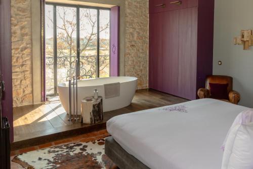 a bedroom with a tub and a bed and a window at Hôtel de Castigno - Wine Hotel & Resort in Assignan