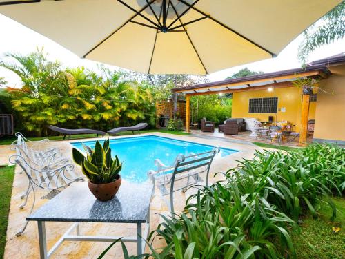 a patio with a table and an umbrella and a pool at Villa Rosalía con Piscina Climatizada in Jarabacoa
