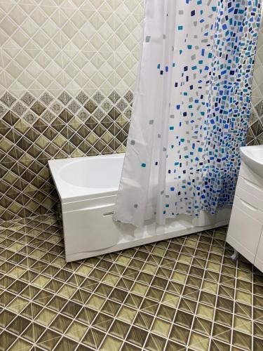 a bathroom with a tub and a shower curtain at Hotel KASIMOV in Podan