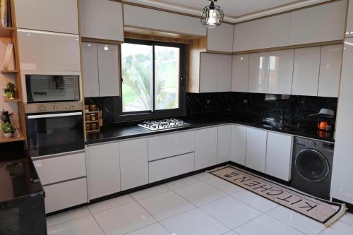 a large kitchen with white cabinets and a window at Villa aya in Oujda