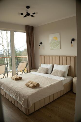 a bedroom with a large bed with two towels on it at Sunrise Yablunytsia in Yablunytsya