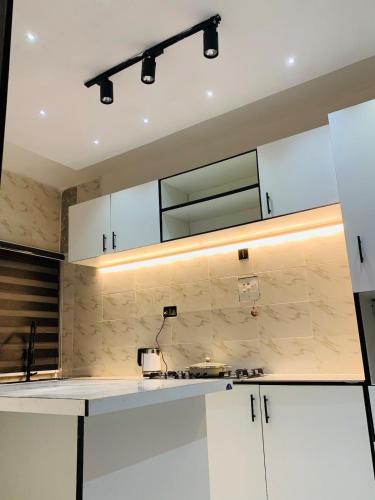 a kitchen with white cabinets and a mirror at 3BED flat close to the airport lagos in Lagos